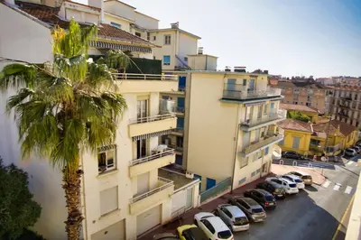 an apartment building with a palm tree and cars parked on a street at Ref JUAS - Palmes d'Or Properties in Cannes