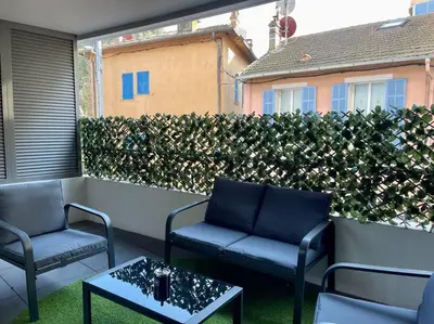 a patio with two chairs and a table and a hedge at 2 pièces près de la Croisette in Cannes