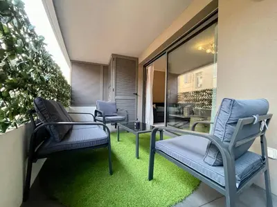 two chairs and a table on a balcony with green grass at 2 pièces près de la Croisette in Cannes