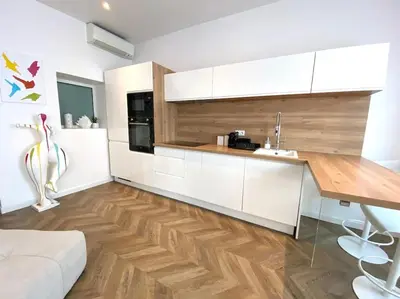 a kitchen with white cabinets and a wooden counter top at Superbe 2 pièces - Cannes Banane in Cannes