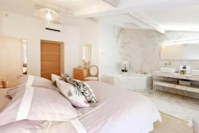 a white bedroom with a large bed and a bathroom at Candy in Cannes