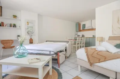 a living room with two beds and a table and a kitchen at IMMOGROOM - Best place in Cannes Center - AC - 5 min from beaches in Cannes