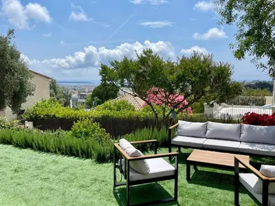 a garden with a couch and chairs on the grass at La Villa d’Emma in Mougins