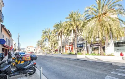 a motorcycle parked on the side of a street with palm trees at 2 Bedroom Amazing Apartment In Cannes in Cannes