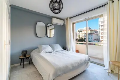 a bedroom with a bed and a large window at Le Mistral - Appt avec deux balcons à Cannes in Cannes