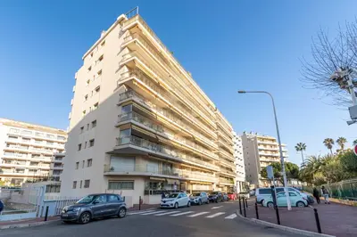 a tall white building with cars parked in front of it at Le Mistral - Appt avec deux balcons à Cannes in Cannes