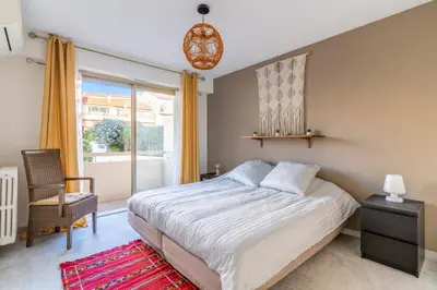 a bedroom with a bed and a chair and a window at Le Mistral - Appt avec deux balcons à Cannes in Cannes