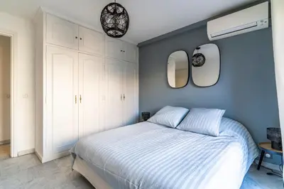a bedroom with a white bed and two mirrors at Le Mistral - Appt avec deux balcons à Cannes in Cannes
