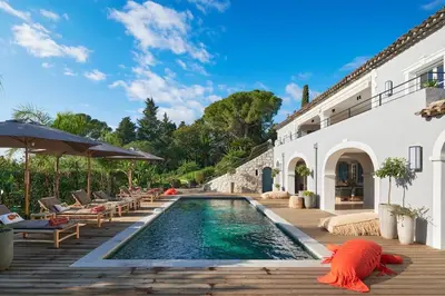 a swimming pool with chairs and umbrellas next to a house at Cannes magnifique villa vue mer basse Californie in Cannes