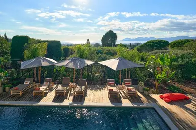 a swimming pool with lounge chairs and umbrellas next to at Cannes magnifique villa vue mer basse Californie in Cannes