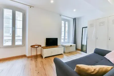 a living room with a couch and a tv at LE NID DU SUQUET une escapade idéale pour couples, près commerces, Palais et plages in Cannes