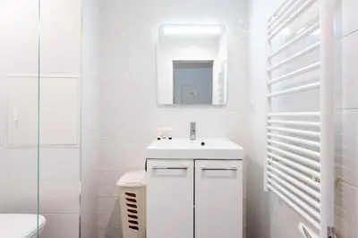 a white bathroom with a sink and a mirror at LE NID DU SUQUET une escapade idéale pour couples, près commerces, Palais et plages in Cannes