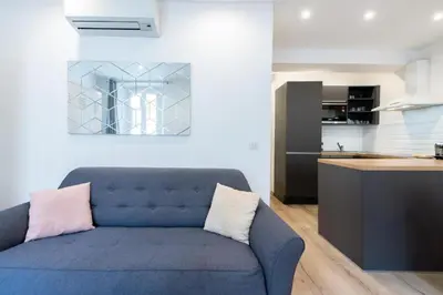 a living room with a blue couch and a kitchen at LE NID DU SUQUET une escapade idéale pour couples, près commerces, Palais et plages in Cannes