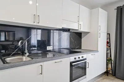 a kitchen with white cabinets and a sink at Appartement Sauvalie - Welkeys in Le Cannet