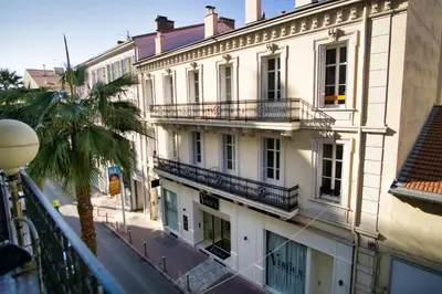 an apartment building with balconies and a palm tree at Ref JOFFRE - Palmes d'Or Properties in Cannes