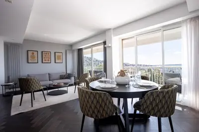 a living room with a table and chairs and a couch at Cannes Panorama - Piscine, vue mer, parking, clim in Cannes