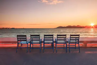 four chairs sitting on the beach watching the sunset at Cannes Studio situé dans la résidence Gallia Historique in Cannes