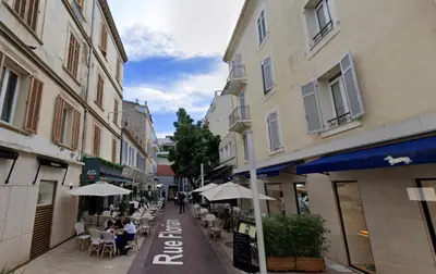a street with tables and chairs and umbrellas at Le Florian By SCLS Locations in Cannes