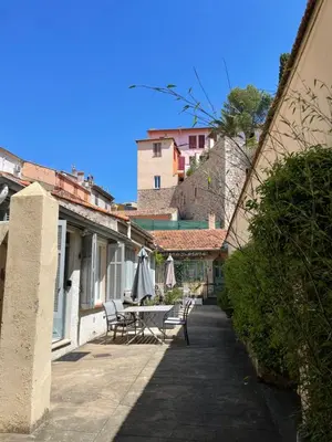 a patio with chairs and a table with umbrellas at Maisonnette Studio bas Suquet, proche plage et palais in Cannes
