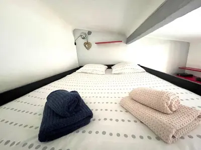 a bed with two pillows and a blue hat on it at Maisonnette Studio bas Suquet, proche plage et palais in Cannes