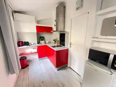 a small kitchen with red cabinets and a white wall at Maisonnette Studio bas Suquet, proche plage et palais in Cannes