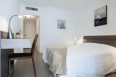 a white bedroom with a bed and a desk at 1-Br apartment in Palm Beach swimming pool in Cannes