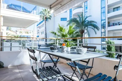 a table and chairs on a balcony with palm trees at 1-Br apartment in Palm Beach swimming pool in Cannes