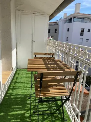 a wooden table on a balcony with green grass at Studio centre ville cannes in Cannes