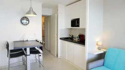 a small kitchen with a table and a blue chair at Appartement 753, 4 personnes, vue mer By Palmazur in Cannes