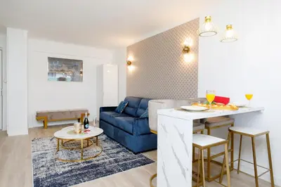 a living room with a blue couch and a table at Perle Dorée YourHostHelper in Cannes