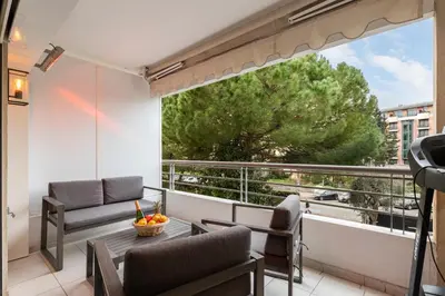 a balcony with a table and chairs and a large window at croisette3bedroomterrasse in Cannes
