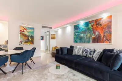 a living room with a black couch and a painting at croisette3bedroomterrasse in Cannes