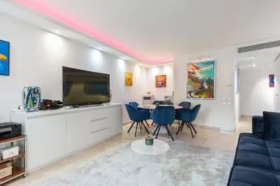 a living room with a tv and a table with chairs at croisette3bedroomterrasse in Cannes