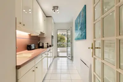 a kitchen with white cabinets and a hallway with a door at croisette3bedroomterrasse in Cannes