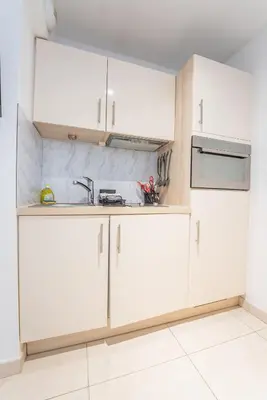 a kitchen with white cabinets and a sink at Joli studio centre Cannes in Cannes