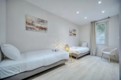 a white bedroom with two beds and a chair at Duplex 5 chambres PATIO, Clémenceau-CENTRE CANNES A5B003 in Cannes