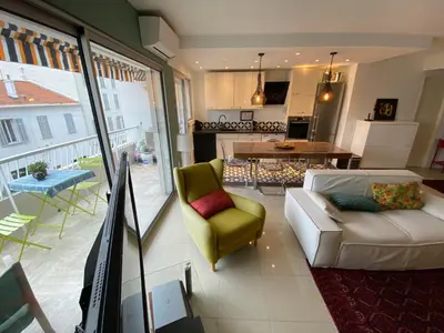 a living room with a couch and a table and a kitchen at Grand appartement de style avec parking - Cannes in Cannes