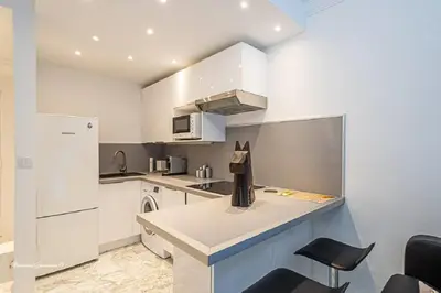 a kitchen with white cabinets and a white refrigerator at Ô 27 Fleurie Cannes in Cannes
