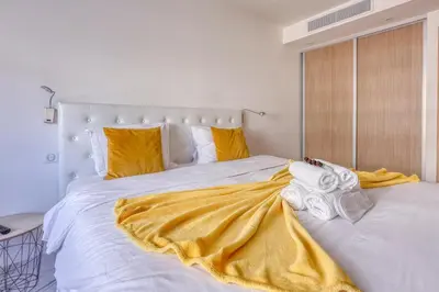 a white bed with a yellow blanket on it at Cannes le Versailles Standing Presta in Cannes