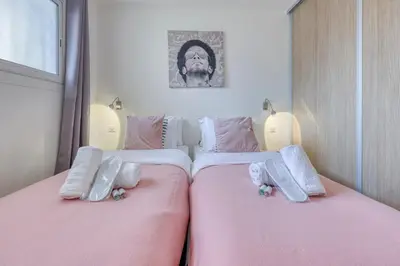 two beds in a bedroom with pink sheets at Cannes le Versailles Standing Presta in Cannes