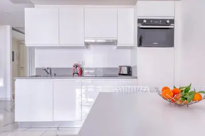 a kitchen with white cabinets and a bowl of oranges at Cannes le Versailles Standing Presta in Cannes