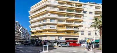 a tall white building with cars parked in front of it at Cannes le Versailles Standing Presta in Cannes