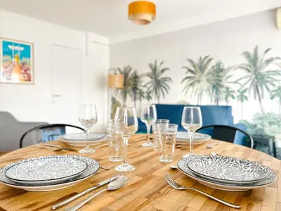 a wooden table with plates and wine glasses on it at Le CozyCroisette - Centre Cannes - 6 personnes in Cannes