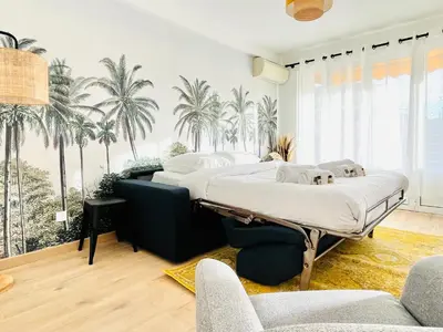 two beds in a room with palm trees on the wall at Le CozyCroisette - Centre Cannes - 6 personnes in Cannes