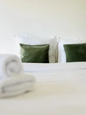 a white bed with white pillows and green pillows at Le Panoramique - 4 pièces centre Cannes in Cannes