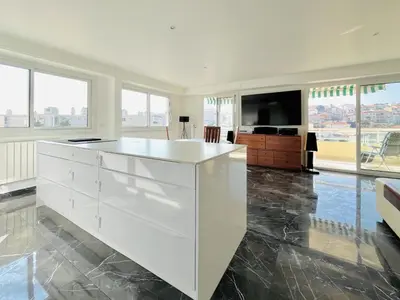 a kitchen with a white island in a room with windows at Le Panoramique - 4 pièces centre Cannes in Cannes
