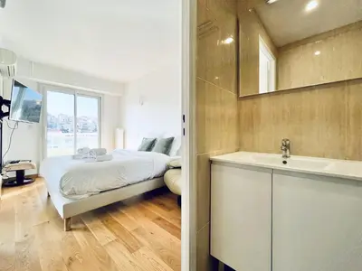 a bedroom with a bed and a sink and a mirror at Le Panoramique - 4 pièces centre Cannes in Cannes