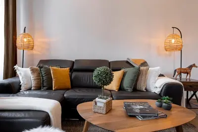 a living room with a black leather couch at L'atelier des Artistes -Écrin de sérénité au coeur de Cannes - Balcon - Clim - Wifi in Cannes