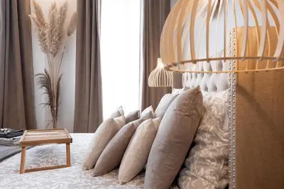 a bedroom with a bed with pillows and a lamp at L'atelier des Artistes -Écrin de sérénité au coeur de Cannes - Balcon - Clim - Wifi in Cannes