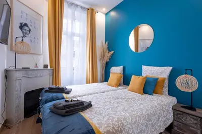 a blue bedroom with a bed and a mirror at L'atelier des Artistes -Écrin de sérénité au coeur de Cannes - Balcon - Clim - Wifi in Cannes